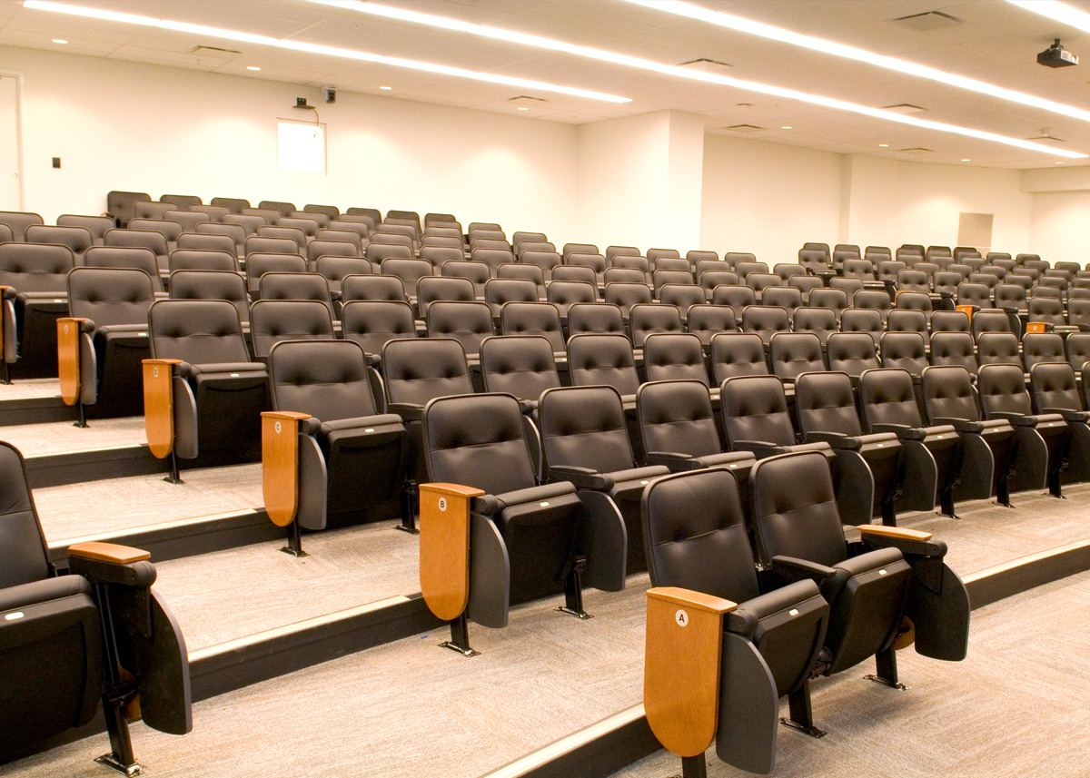 A lecture with eleven rows of black leather tablet arm chairs.