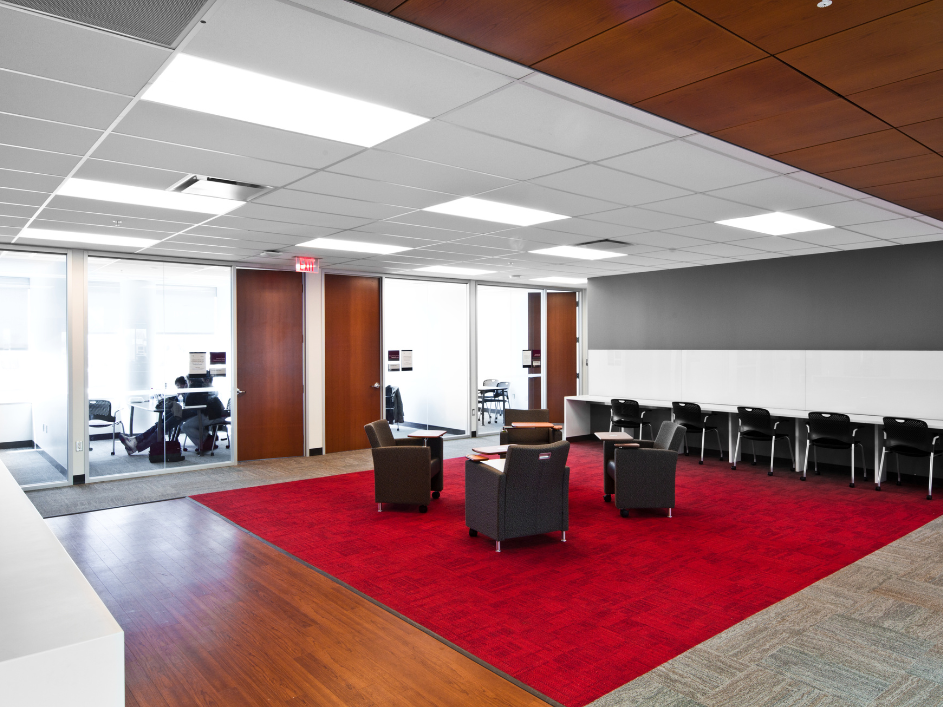 Four armchairs are arranged in a circle in a lobby area on a red and grey carpet.